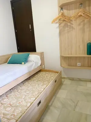 a small bedroom with a bed and a cabinet at Apartamento Vip la Barrosa in Chiclana de la Frontera