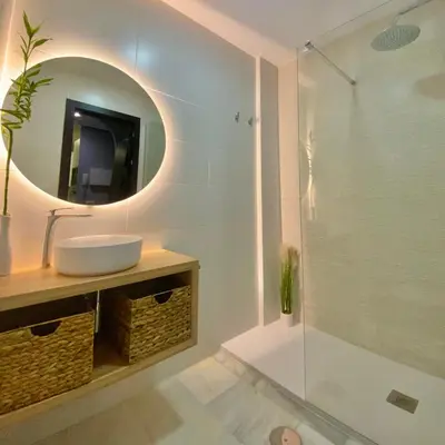 a bathroom with a sink and a shower with a mirror at Apartamento Vip la Barrosa in Chiclana de la Frontera