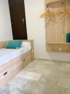 a bedroom with a bed and a wooden cabinet at Apartamento Vip la Barrosa in Chiclana de la Frontera