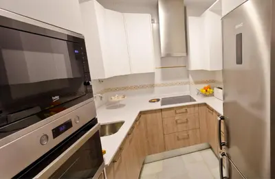 a kitchen with white cabinets and a large television at Apartamento Vip la Barrosa in Chiclana de la Frontera