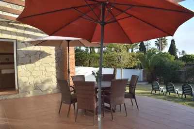 a table and chairs under an umbrella on a patio at Villa María Elena, en Fuente del Gallo in Conil de la Frontera