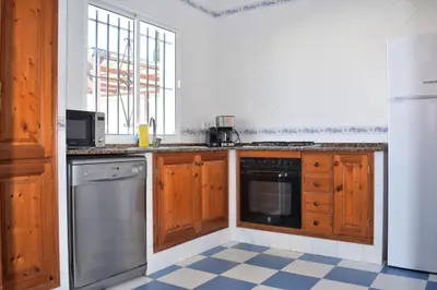 a kitchen with wooden cabinets and a dishwasher at Villa María Elena, en Fuente del Gallo in Conil de la Frontera