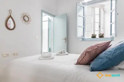 a bedroom with a large white bed with pillows at Apartamento Floral by LiveWork in Cádiz