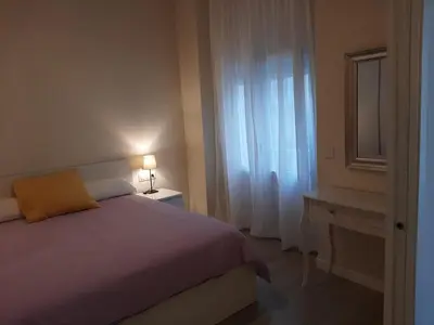 a bedroom with a bed and a mirror and a window at La esquina de los italianos by Gades Gestión in Cádiz
