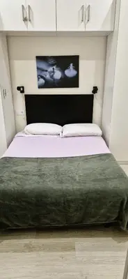 a bedroom with a large bed with a green blanket at La esquina de los italianos by Gades Gestión in Cádiz
