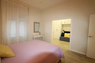 a bedroom with a pink bed and a mirror at La esquina de los italianos by Gades Gestión in Cádiz