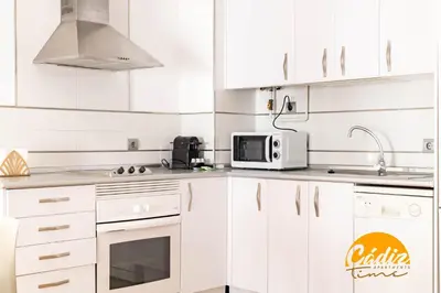 a white kitchen with white cabinets and a microwave at Corazon del Mar - FREE PARKING by Cadiz Time in Cádiz