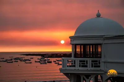 a sunset with boats in the water and a building at Corazon del Mar - FREE PARKING by Cadiz Time in Cádiz
