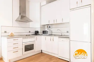a white kitchen with white cabinets and a refrigerator at Corazon del Mar - FREE PARKING by Cadiz Time in Cádiz