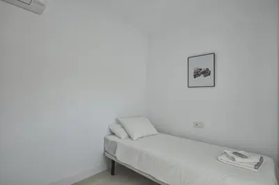 a white room with a bed and a picture on the wall at Barrosa Frente al Mar in Chiclana de la Frontera