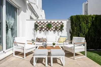 a patio with white chairs and a table and a couch at CASA LA PLAYA-CONIL Vacaciones de Lujo en Conil con Todas las Comodidades NETFLIX-HBO-DISNEY-CANALES DE FUTBOL-WIFI ALTA VELOCIDAD-SMART TV 65
