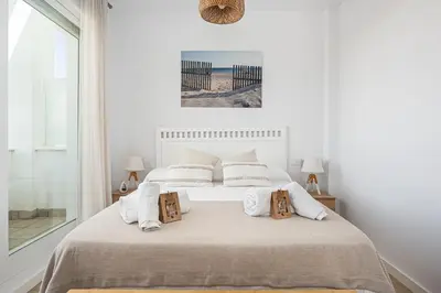 a white bedroom with a large bed with pillows at CASA LA PLAYA-CONIL Vacaciones de Lujo en Conil con Todas las Comodidades NETFLIX-HBO-DISNEY-CANALES DE FUTBOL-WIFI ALTA VELOCIDAD-SMART TV 65