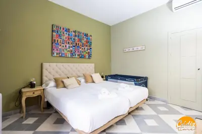 a bedroom with a large white bed with a painting on the wall at Blue Home by Cadiz Time in Cádiz