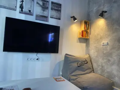 a living room with a tv and a chair at LA CUEVA DEL LOCO, Bretones 29 in Sanlúcar de Barrameda