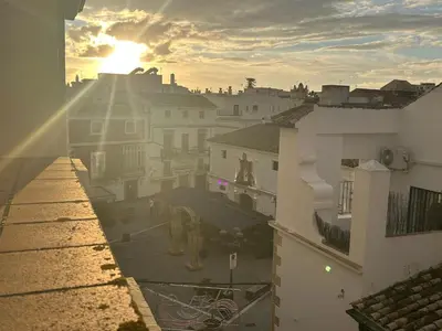 a view of a city with the sun setting behind buildings at GATU Herrería in El Puerto de Santa María