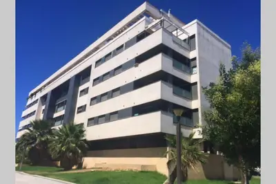 a large white building with palm trees in front of it at GATU PREMIUM El Puerto Centro aire acc, calefacc, wifi, parking y piscina comun Preferente mayores de 25 años y familias 