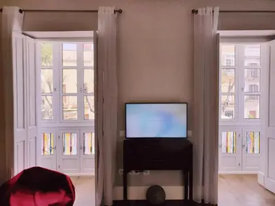 a living room with two windows and a flat screen tv at Sherryflat Plateros in Jerez de la Frontera