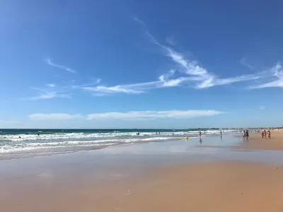 a group of people on a beach with the ocean at Precioso apartamento muy cerca de la playa in Chiclana de la Frontera