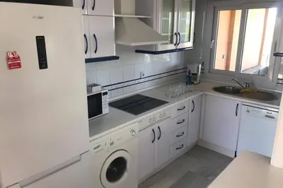 a white kitchen with a sink and a washing machine at Precioso apartamento muy cerca de la playa in Chiclana de la Frontera
