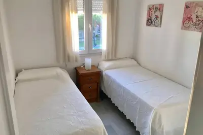 two twin beds in a room with a window at Precioso apartamento muy cerca de la playa in Chiclana de la Frontera