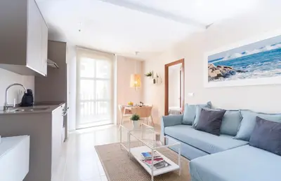 a living room with a blue couch and a kitchen at APARTOYOU PREMIUM - Apartamentos Casa Linares in El Puerto de Santa María