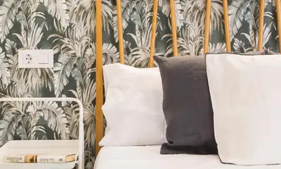 a bed with two pillows and a wall with plants at APARTOYOU PREMIUM - Apartamentos Casa Linares in El Puerto de Santa María