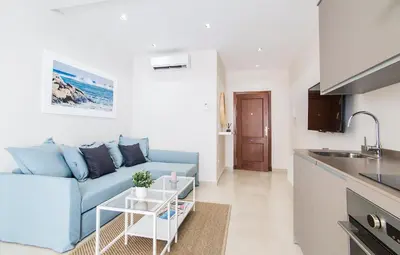 a living room with a blue couch and a kitchen at APARTOYOU PREMIUM - Apartamentos Casa Linares in El Puerto de Santa María