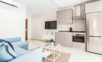 a living room with a blue couch and a kitchen at APARTOYOU PREMIUM - Apartamentos Casa Linares in El Puerto de Santa María