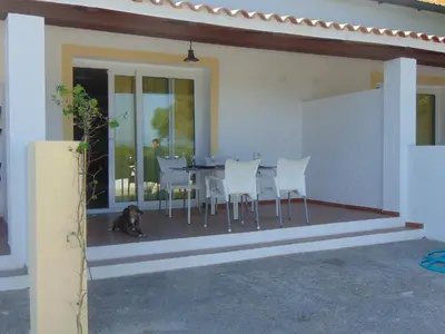a dog laying on the porch of a house with a table and chairs at Finca La Parrilla in Arcos de la Frontera