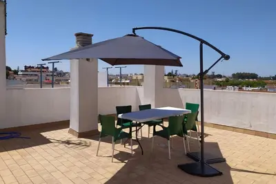 a table and chairs under an umbrella on a roof at Atico La Estacion in Sanlúcar de Barrameda