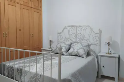 a bedroom with a white bed and two night stands at Atico La Estacion in Sanlúcar de Barrameda