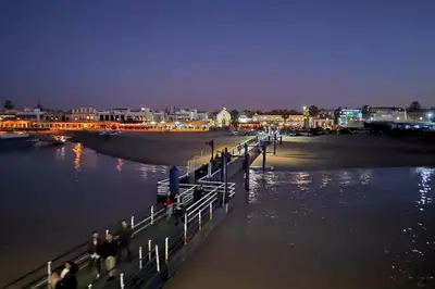 a group of people standing on a pier near the water at Atico La Estacion in Sanlúcar de Barrameda