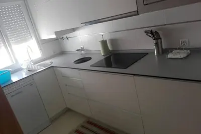 a white kitchen with a sink and a counter at Atico La Estacion in Sanlúcar de Barrameda