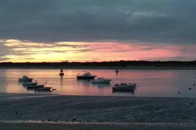 a group of boats in the water at sunset at Atico La Estacion in Sanlúcar de Barrameda