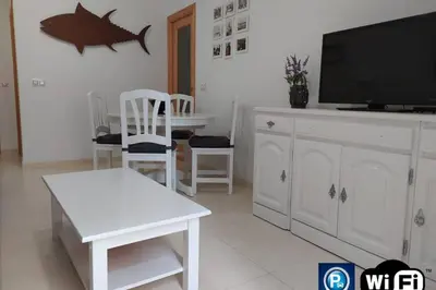 a living room with a television and a table and chairs at Atico La Estacion in Sanlúcar de Barrameda