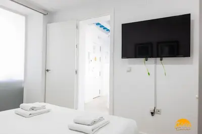 a white bedroom with a tv on a wall at Apartamento Oceano by Cadiz Time in Cádiz