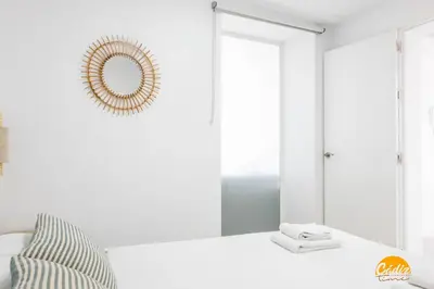 a white room with a mirror and a bed at Apartamento Oceano by Cadiz Time in Cádiz