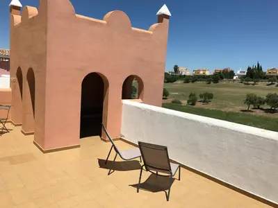 a patio with two chairs and a wall at Flamingo Golf B in Sanlúcar de Barrameda