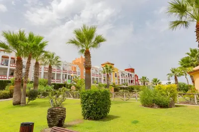 a park with palm trees and buildings in the background at Flamingo Golf B in Sanlúcar de Barrameda