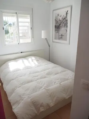 a white bed in a white bedroom with a window at Flamingo Golf B in Sanlúcar de Barrameda