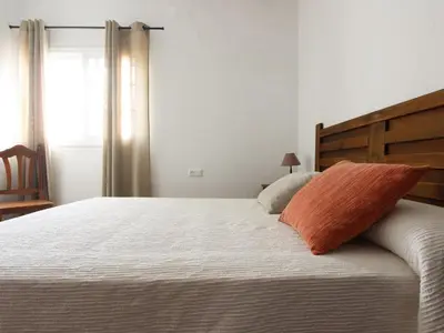 a bed with an orange pillow on top of it at VILLA ELLY in Conil de la Frontera