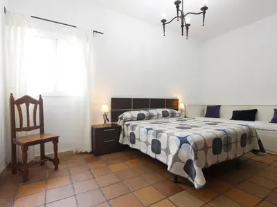 a bedroom with a bed and a chair and a window at VILLA ELLY in Conil de la Frontera
