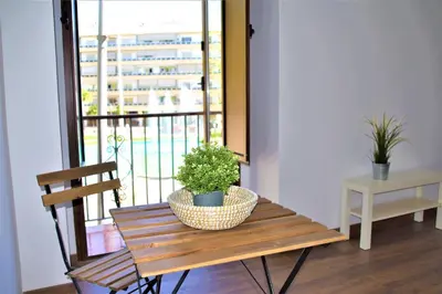 a wooden bench with a potted plant on it next to a window at Apartamentos Turísticos Mamelón in Jerez de la Frontera