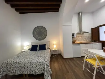 a bedroom with a bed with a table and a kitchen at Apartamentos Turísticos Mamelón in Jerez de la Frontera