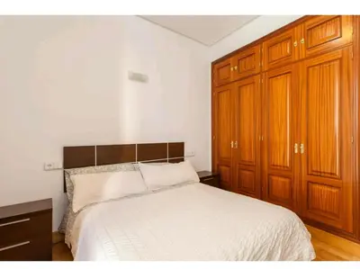 a bedroom with a white bed and wooden cabinets at Atico padre Aldama centro y con WIFI in Sanlúcar de Barrameda