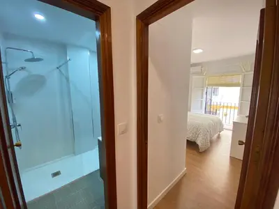 a glass shower door in a room with a bed at Sánchez Home, Pleno Centro in Sanlúcar de Barrameda