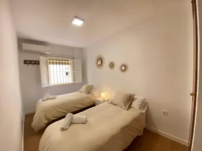 a room with two beds and a window at Sánchez Home, Pleno Centro in Sanlúcar de Barrameda