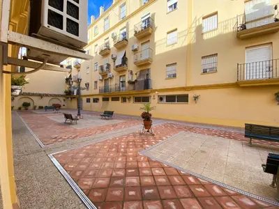 an empty courtyard of a large building with benches at Sánchez Home, Pleno Centro in Sanlúcar de Barrameda