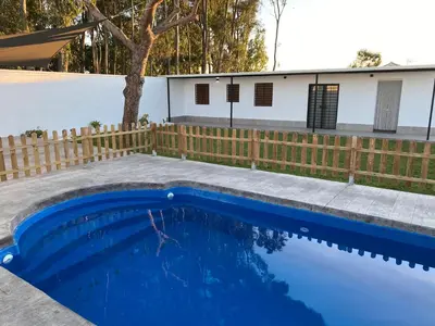 a blue swimming pool with a fence and a house at Chalets Novo Sancti Petri in Chiclana de la Frontera
