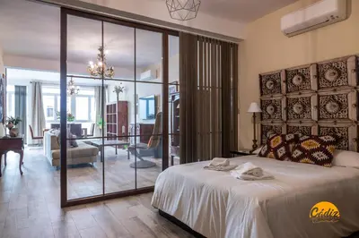 a bedroom with a large bed and a living room at La Luz de Cadiz by Cadiz Time in Cádiz